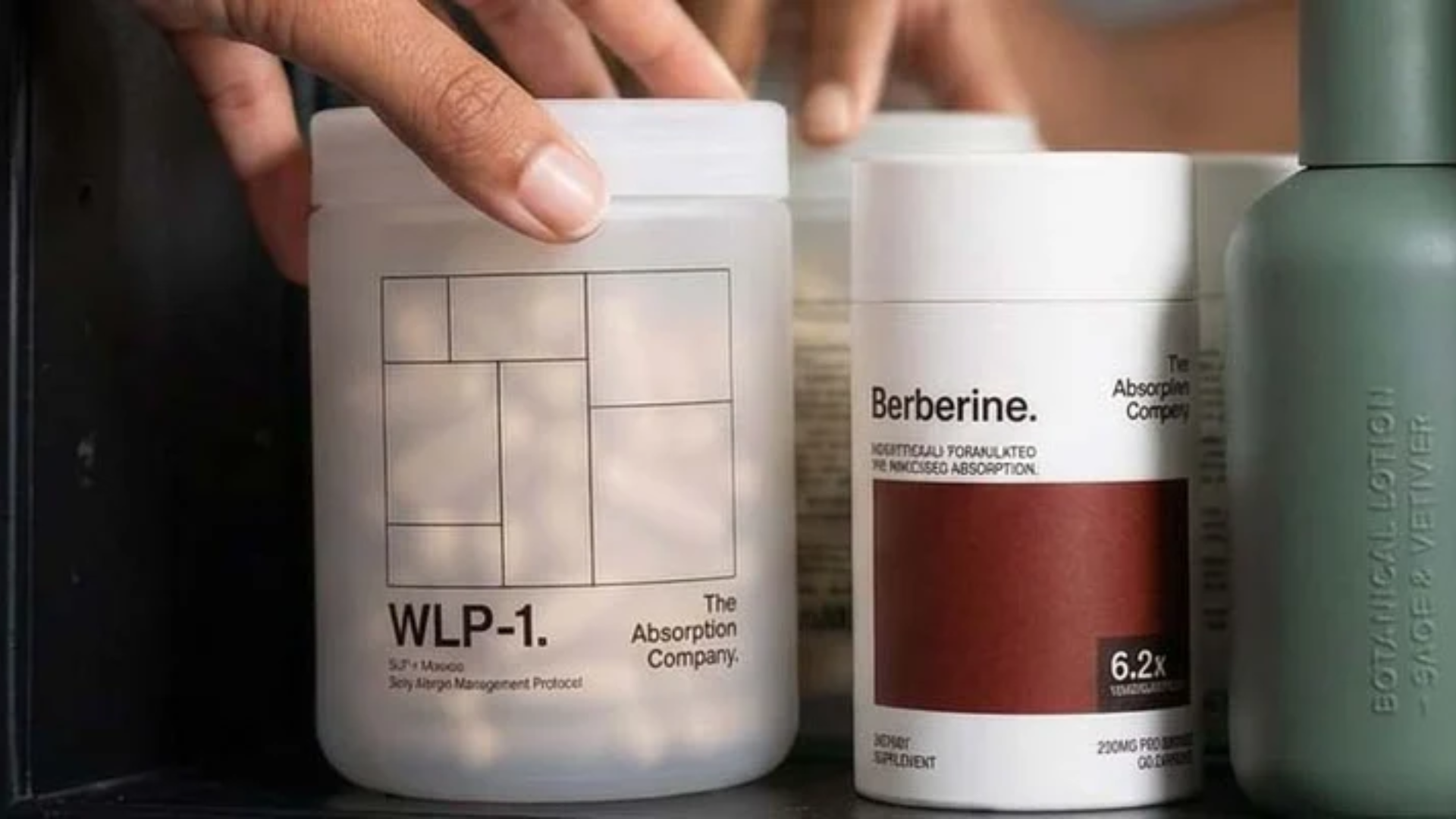 Hand reaching for WLP-1 bottle on a shelf with Berberine and other Absorption Company products.