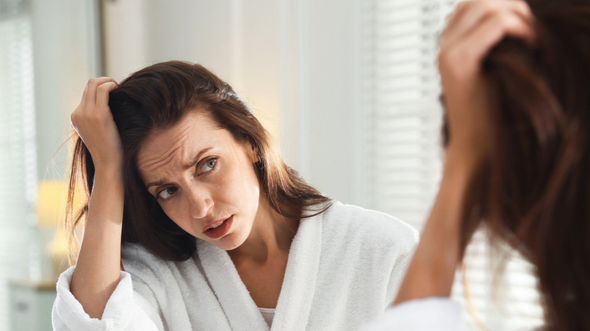 Woman examining hair loss in mirror after stress